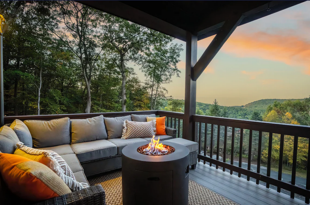 Covered deck with fire pit and sectional overlooking the Shenandoah ridgeline at sunset