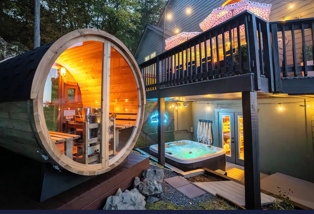 Cedar barrel sauna and hot tub at the retreat cabin at dusk